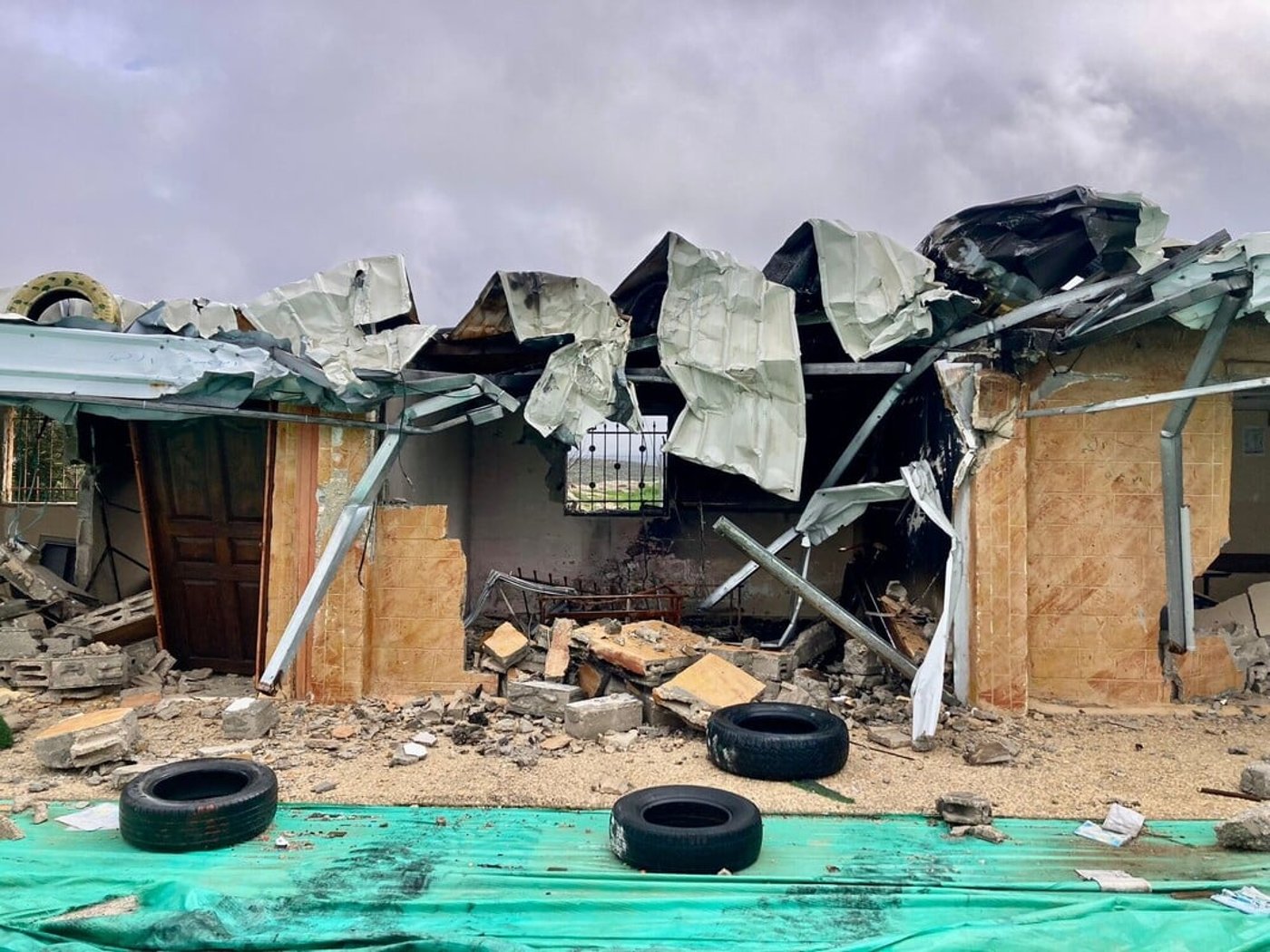 Ett svårt skadat bostadshus med raserat tak, förstörda väggar och bråte efter en explosion eller beskjutning.