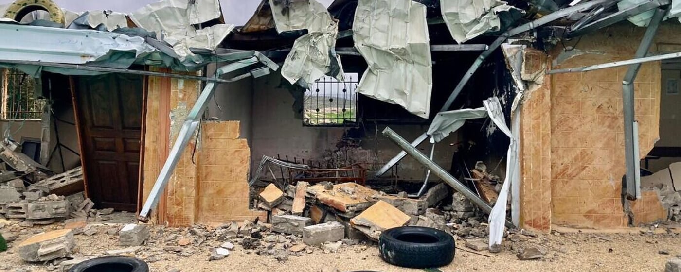 Ett svårt skadat bostadshus med raserat tak, förstörda väggar och bråte efter en explosion eller beskjutning.