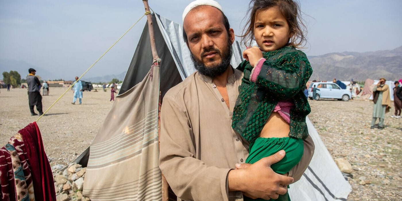En man håller sin dotter utanför ett provisoriskt tält i ett läger för internflyktingar i östra Afghanistan.