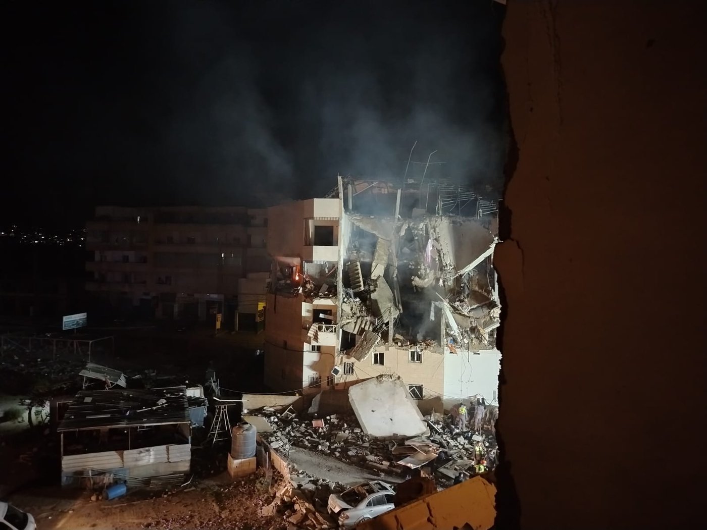 En svårt skadad byggnad syns i mörker, med stora delar av fasaden raserade.