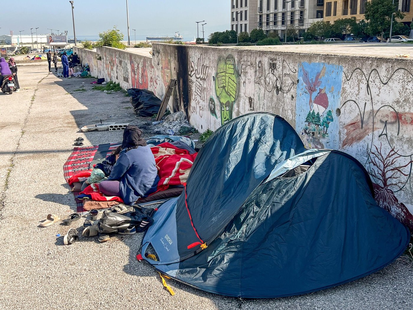 Fördrivna familjer sitter och vilar bredvid sina tillhörigheter utanför små tält längs en gata i Beirut.