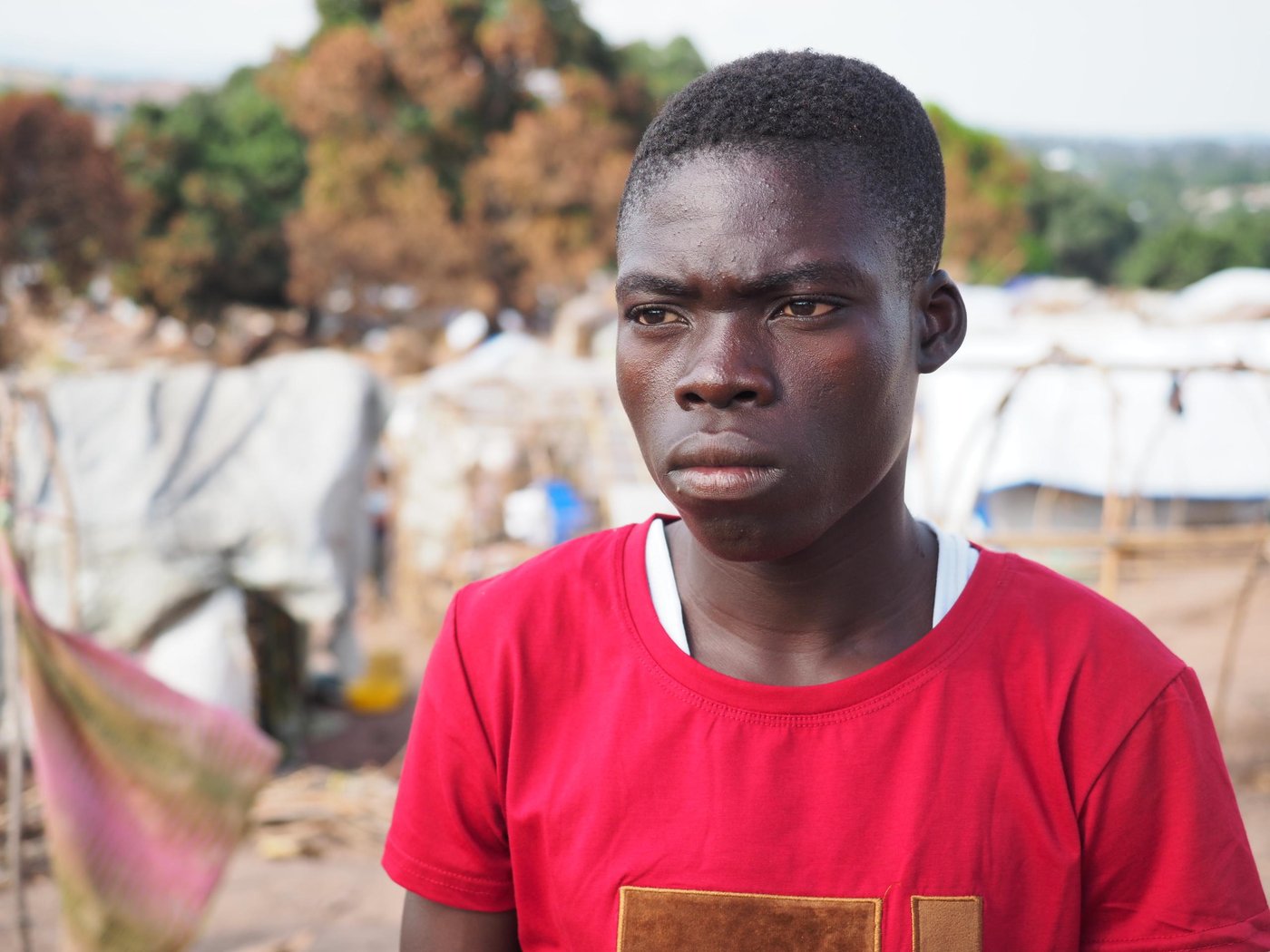 Masimango and Bone are brothers and they live together in an IDP camp in the Tanganyika Province. Masimango is 18 years old and fled for the first time in his life with his younger brother Bone who is 8 years old. They used to have a completely normal life back home in Nyunzu, but one afternoon two years ago, there was a clash between ethnical armed groups and they attacked the village. Masimango and Bone had done older sister and one older brother, but they both died during the attack. Their parents were killed as well. They still have some surviving relatives, but they fled to other villages so haven’t kept in touch. Masimango and Bone fled for hours until they reached a safe place where they were given a lift together with some other refugees from the village, with the train to Kaseke.
The life in the IDP camp is very difficult. They are in a lack of food and they can only eat when they receive support and assistance from a NGO, or other people if they are lucky. They depend on support from humanitarian organisations like NRC. NRC has supported them with 50 USD so they received things they need in order to protect themselves and survive. They got a plastic sheet to protect their temporary shelter. If they don’t receive support from NGOs, the only option they would have is to beg. Masimango and Bone has some friends in the camp including an elderly person who support them and sometime provide the food and water.
Masimango is only 18-year-old, and he feels a big burden because he needs to be strong for his younger brother, despite the challenges they meet every day. He is very sad over the situation that they are suddenly in. It’s hard for him to be the only responsible person for his younger brother. The huge life change happened so quickly and they’ve made such a big impact on their lives. Being a displaced youth with no parents who can support them is extremely difficult. They hope for their future to be brighter.
Masimango wishes that he and Bone can go back to school. He had to drop out of school in 6th grade in primary school. Masimango would like to become an aid-worker so he can assist other people in need due to the on-going conflict. Masimango misses his family and his old life so much, but he tries to stay optimistic and says that as long as he gets food, he can stay strong and alive so he will eventually find a job. It’s all about surviving day-by-day.
Photo: Ingrid Prestetun/NRC