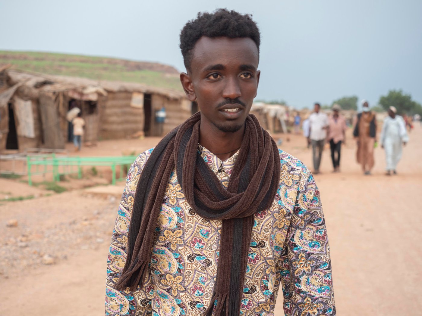 In November 2020 Aklilu packed his bags for a trip from his university in Addis Ababa, the capital of Ethiopia, to meet his family in Humera, a small town nestled in the most northwestern part of the country. Like other soon-to-be college graduates, Aklilu was already job hunting and planning to celebrate. “I’ll see you in five weeks for our graduation ceremony,” Aklilu told his friends.
A few days after Aklilu returned to his family home in Humera, mortar-fire ripped through the small town. Conflict started between the federal government of Ethiopia and the Tigrayan Defence Force. Aklilu hurried across the border into Sudan for safety. Today, over 60,000 Ethiopians have poured into Sudan for safety like Aklilu.
Aklilu fled into Sudan with nothing and left his education in Ethiopia behind. Once proficient in the backroom politics of Chelsea football club and a top structural engineering student, Aklilu kicks dirt and waits for updates about the war in Ethiopia. He wonders if the past five years of college education have been for nothing.
“We never expected this could happen. I had heard there were issues, but to me they were just politics. I never knew things could become this bad,” Aklilu says.
When Aklilu arrived at the Um Rakuba refugee camp he lived with his mother, brother, grandmother, aunt, uncle and cousins under a blue tarp that hung over bundled-together wood. A latrine was nearby and the smell overtook the morning coffee his grandmother made. A few weeks later, his family relocated to another space and were given a white tent with a gracious opening in the front and back. But in the rainy season the tent became a parachute. Aklilu and other refugees became bleary eyed by holding the tent down each night to stave off the winds.
“When I was in Ethiopia, I loved the rainy season. You can’t do anything but sit and watch the rain come down. That was my favourite moment,” says Aklilu.
Around 1,655 other university students feel abandoned in the refugee camps like Aklilu. In Umm Rakuba there are 76 university students who have formed a group, called the Tigrayan Refugees University Students in Sudan Association, or TRUSS. The association’s document lay out why their future is in doubt.
“Going back is like choosing death,” one letter the association wrote to a visitor says. “Universities in Tigray are highly damaged and destroyed…universities outside of Tigray are giving services at this time but most Tigrayan University students are afraid to go there because of their identity." Youth like Aklilu cannot back home to continue their education in the universities of Ethiopia in fear of the violence and discrimination they might encounter for being Tigrayans.
“A result of the conflict in Ethiopia is that some of the brightest minds in the country are confined to refugee camps in Sudan,” said Will Carter, Sudan Country Director at the Norwegian Refugee Council. “If these students are given a chance somewhere, they’d be a spark for whomever accepts them.”
But TRUSS students want more than acceptance into a University — they want a university to recognize their past work.
Many hurdles stand in the way of Aklilu getting his degree. When the violence started, many like Aklilu fled and left behind most of their valuables, including their civil documents, identity cards, and education records. As result, they are now unable to provide proof for who they are or how far along they got in university. Also, in a camp where the scarce amount of money they have is barely enough for food, the students cannot afford paying for registration, books, transportation, and accommodation. The only solution would be a full-board scholarship.
Recently, Aklilu has been exploring going to a university in Ghana under a scholarship. However, this scholarship likely means that students lose the progress they have made in university and start from scratch.
Aklilu, like the other senior students in the camp, is frustrated that he probably has to spend another five years studying for a Civil Engineering Degree he was only five weeks away from receiving.
“We are waiting for the opportunity for a university that will accept to acknowledge the credit we have from the university back home. If we accept to start over, we will be 30 years old by the time we graduate. We might not find a job for a long time over. We will be wasting a lot of time in our life,” says Aklilu.On a Friday morning, members of the association gather in a communal tent for their weekly meeting. They have organized themselves into committees and are planning their week ahead. One group will fundraise among other refugees to help an isolated elderly woman in the camp; another one will meet other students and youth in the camp to connect them with NGOs.
While they wait for education, the students in TRUSS and other youth act like community mobilizers. Truss has been helping organizations like NRC to re-build shelters, organize cash distributions, facilitate children registration in school, as well as raising community issues. They receive stipends from organizations, which help them support their families.
“I liked watching movies and series back home, but I like it even more now because there’s nothing much else to do,” says Bisrat, one of Aklilu’s close friends, who now works for NRC.
The students feel trapped in part because they are. The 2014 Asylum Act gives refugees the right to move and seek an education, but in reality, they are contained to the camp. The encampment policy enforced for refugees prevents all the residents to leave the site, cutting them access to jobs and markets and curtailing their freedom of movement.
“Tigrayan refugees cannot leave the camp unless they acquire a permit from authorities for worthy reasons, linked to education, health, or jobs. Unfortunately, these permits are very hard to get – it becomes a vicious circle. They can’t get many opportunities to leave the camp, if they can’t leave the camp to look for them,” says Silvia Beccacece, former NRC Gadarif Area Manager.
Kids in the camp get access to education but are not much better off. Thanks to help from the Norwegian Ministry of Foreign Affair, NRC was one of the first organizations to respond to learning needs in Umm Rakuba. Since then, NRC has been able to expand the quality and durability of the schools with the help of Education Cannot Wait. Around 2,050 children, aged between 6 and 14, go to the four schools NRC has built in different areas of the camp. Resources remain limited. The only textbooks available were ferried across from Ethiopia, and the children attend their classes by sitting on the floors of sand.
Still, students are grateful for what they receive. Nati Teame, 10, is one of NRC’s schoolchildren in the Um Rakuba camp.
“I wake up in the morning and pass the time until it’s time for school. I’ve never been late,” Nati said. “My parents never got the chance to be educated, and I don’t want the same thing to happen to me.”
Photo: Ingrid/Prestetun