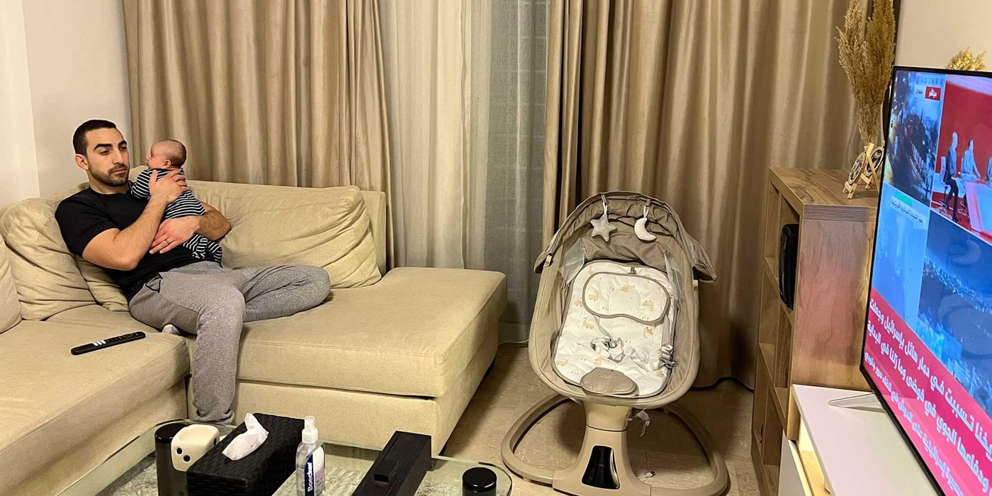 En pappa och hans bebis tittar på nyheterna hemma.