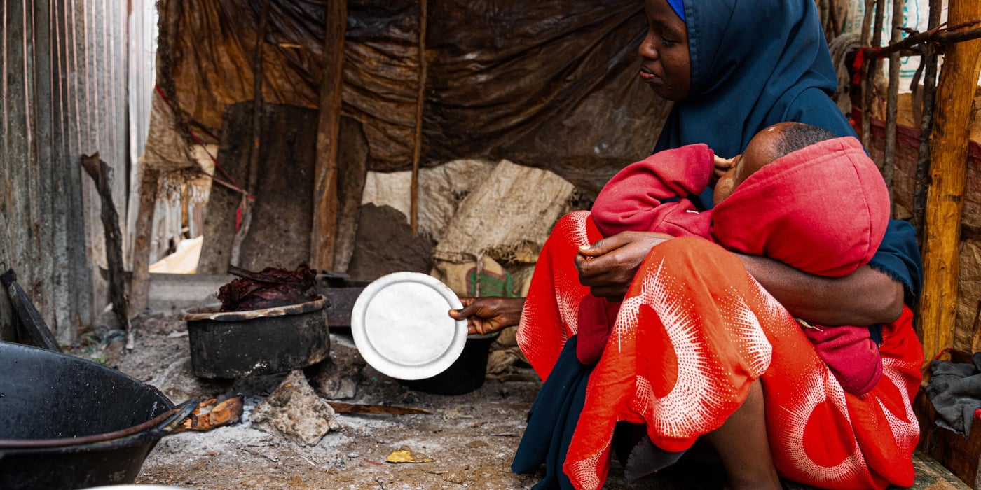 En kvinna håller ett barn utanför ett tillfälligt skydd i Somalia.