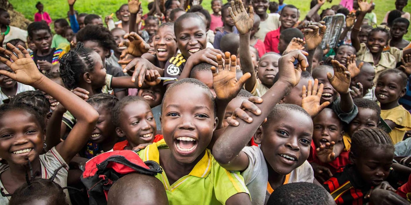 Children in the Central African Republic smiling and waving at the camera.