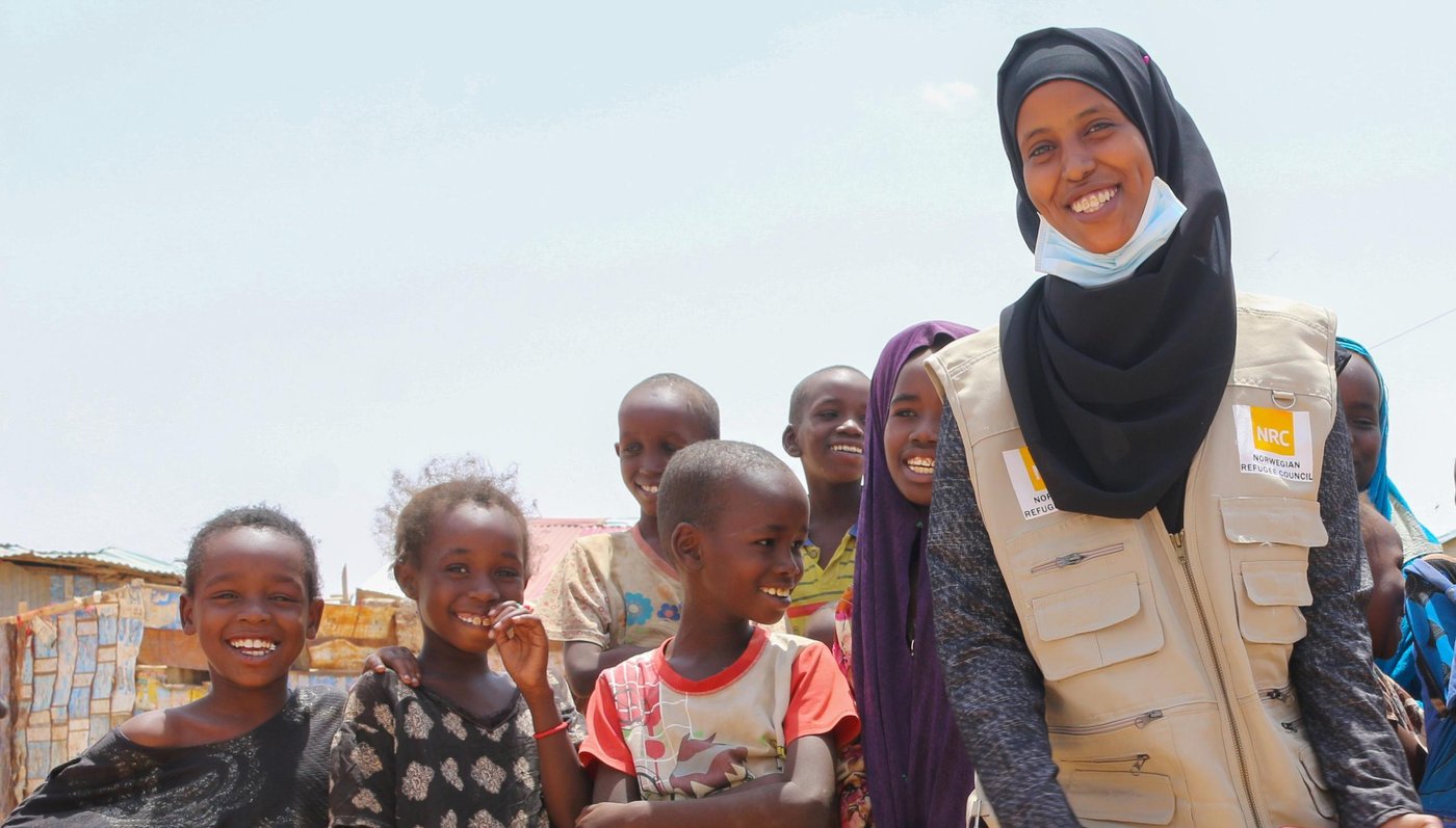 Ifrah Ahmed Abbas posing a photo with a group of children during her visit to one of the biggest IDP settlements in Garowe town, Puntland state of Somalia. Photo: Khadar/NRC.