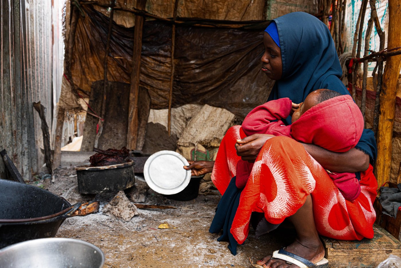 En kvinna håller ett barn utanför ett tillfälligt skydd i Somalia.