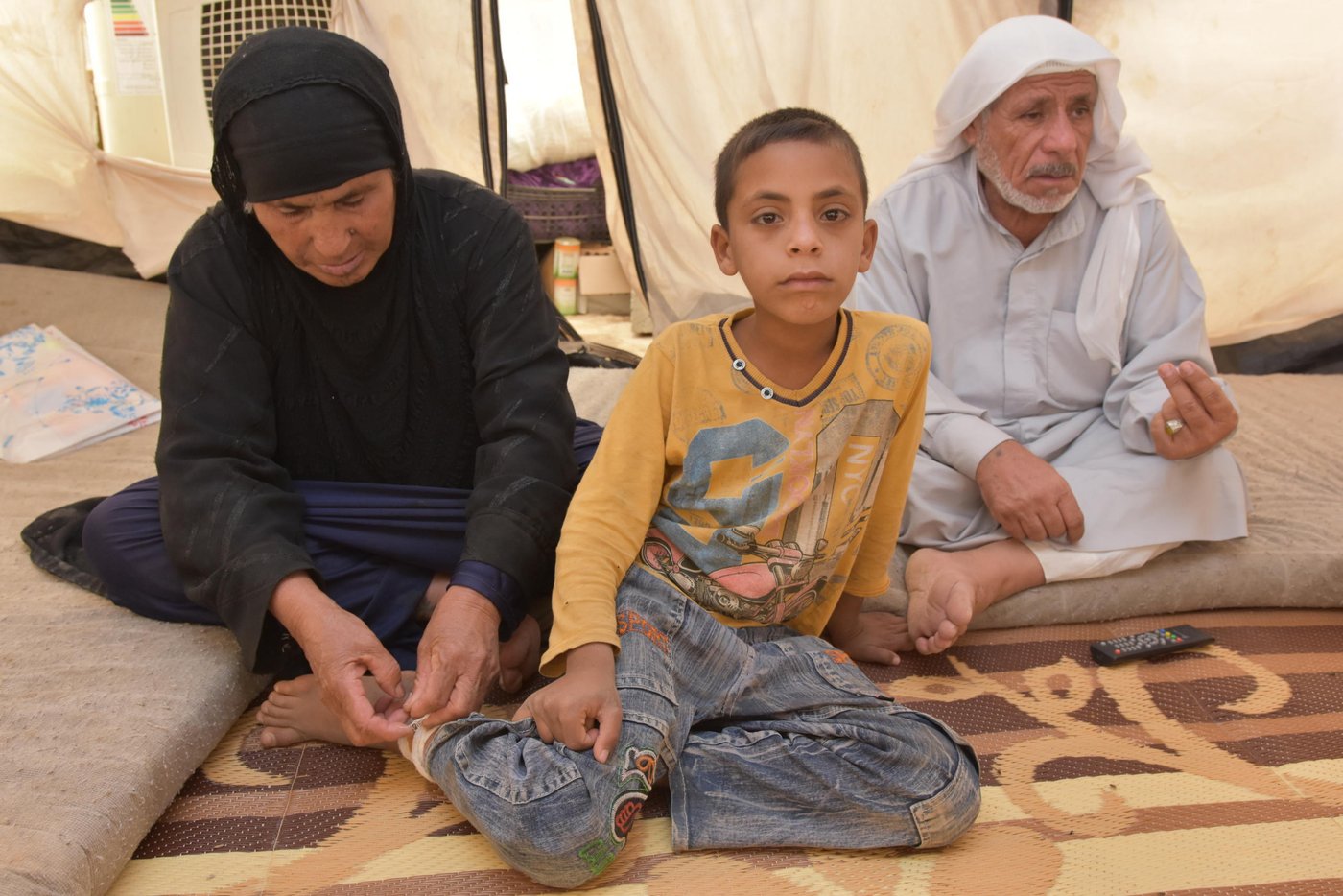 Najma Zarzor Hassan (born 1954) and Fathi Jasim Mohammad (born 1946) with four of their grand children. The three boys are brothers, the girl is the daughter of another son. 
Azer (8) (yellow sweater, sitting with his grandmother)  is Ahmed’s cousin. Azer is one out of many Iraqi children who has suffered tragic losses. For two years from 2014 - 2016, IS controlled the place the family comes from.  
“ISIS blew up my school, I want a new one”, the little boy says. It is in November 2016 and the 8-year-old is living with his grandparents in Debaga camp 2. The grandparents are also taking care of Azer’s two brothers Nehro (5) and Fathi (10) (also in the picture). The boys’ father was killed by ISIS, accused of collaboration with the Iraqi military. Their mother was killed in a bomb blast four months ago, when military forces attacked the village in order to free it from ISIS. Azer was injured in the same bomb explosion that killed his mother. 
His grandmother carefully changes the bandage on his right leg. “He got treatment here in the camp yesterday. He still has several fragments from the blast in his leg and three in his head”, she says, pointing at the blast injuries.  “Look, here. Here. Here. They are so many of them.” 
“My other son crossed a minefield close to the village. He lost his eyes. The area around the village is full of booby traps”, says grandfather Fathi. 

Fathi describes how ISIS killed innocent people with horrible brutality, and says that when the Iraqi army withdraw and ISIS took control, it got worse. “They started to be very hard with us. They would even kill kids like this little ones.“ 
“They, ISIS, are deprived from any kind of human feelings and standards. A life has no value at all. I am 70 years old and even in my generation we have never seen this evil. They have no human principles, no religion. And they come from all countries“, he says.  
“A smoker could not smoke a cigarette, men had to grow a beard. Pants had to be long, reach to your legs. All breaches on the rules were punished. The provided each family with only 5 kilo of flour, that is nothing. 

“Since we came here, it was better. After the airplanes came to liberate us. The Army advanced. Our areas being liberated. There was some losses, but it is better than being under ISIS control.” 

“At the moment there is no future for my grandchildren. As long as me and their grandmother we will take care of them. My son who was killed was educated and graduated, he worked with us at our farm. We were farmers. Now we have nothing and we are doing nothing“, says Fathi Text / photo by Hanne Eide Andersen/NRC