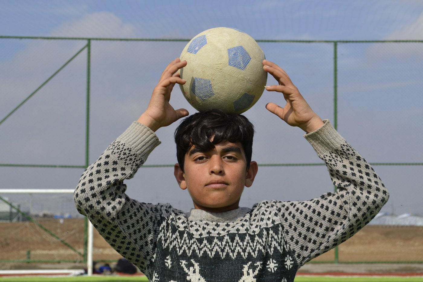 Adnan, a young boy from Sinjar, has lived in Hamam Al-Alil camp for six months. He’s a big fan of the football team Barcelona, and as any Barcelona fan, Messi is his favorite football player. “We used to walk around the camp because we had nothing else to do, or play football in a muddy area around the camp.” Now, the football field in Hamam Al-Alil has become a source of joy for youth and children like Adnan.
Photo: Helen Baker/NRC