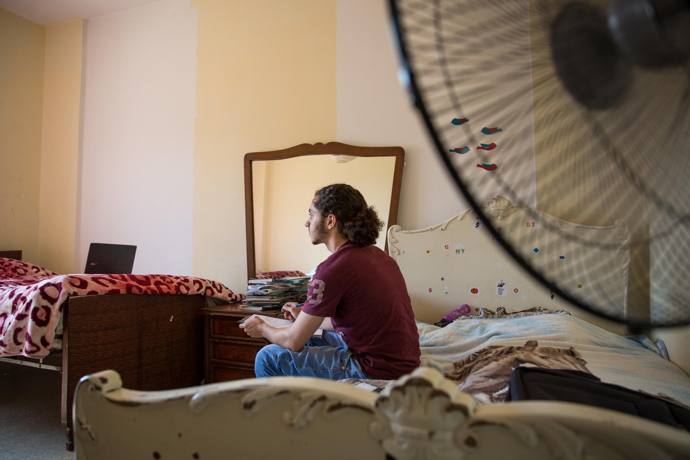 When Osama was 15 years old he fled from the war in Syria together with his parents and four siblings. Now, five years later, he is 20 years old and has just seen his dreams for the future shattered yet another time. 

Osama grew up in the outskirts of the Syrian capital, Damascus. A modern, vibrant and stable city until the war broke out in 2011. He lived a normal life. Went to school. “My country was a nice place to live in. I reached grade 10 in this school. I loved being there,” says Osama. “We lived in an area like Beirut. There were buildings and streets, it was not a village. Our flat was on the ground floor, with three rooms and two gardens. It's awful, because when I was a child, I had a dream to build my future life in that area. I wanted to become a doctor, and open a clinic in my house. My father and mother used to tell us, my siblings and I, that we will transform the house into a medical centre, each room for each one of you.  But we cannot do it now. So, I should find alternative solutions, alternative dreams.”
				
“Maybe you heard about the chemical attacks in 2013? We were near the spot where the chemical attacks happened. After the attacks, president Obama said that he will attack Syria or some points in Syria, so we left. We decided to leave Syria for 3 months, we hoped that the condition in our country would become safer. But the conditions stayed the same, not stable.”
			
“Maybe I should start with the positive things. I am a student in the university. I got a scholarship here. My family is with me. I am sure this is a good thing. My friends' families stayed in Syria.” The dream of becoming a doctor and open a clinic is put on hold for Osama. “Now, I am a computer science student, maybe I will find myself there. I hope I can open a mobile school to teach people.” To be closer to university, Osama lives in a shared flat with nine other Syrian youths in central Beirut. They are close knit group who support each other through thick and thin. His family rents an apartment outside Beirut, and Osama spends his weekends there with them. 

For a Syrian refugee living in Lebanon, there are many limitations. Osama and his older sister are the breadwinners of the family and feel the big burden on their young shoulders. “Even if you found an opportunity to complete your education, and you have a master degree or a PHD for example to become a doctor, you are not allowed to work. Living here is very expensive, so you need a lot of money. My biggest challenge is that the economic situation is so bad, not for me, but for all the Syrian families.”, says Osama. 

“Maybe the bad things here, as a Syrian guy in Lebanon, there are a lot of regulations that restrict my life, which make me not like a normal guy. Right now, I don’t have an official residency, so I cannot go to every place I want. I entered Lebanon legally, but you have to pay $200 per year for each person above 15 years old for a residency permit. So, if your family consists of seven members like ours, you have to pay $1000 yearly. I didn't pay, so they took my passport and now I cannot move or leave this country.” 

Osama and his family have tried to find another way to build their future elsewhere. They applied for resettlement. After a long process, including two interviews, Osama got the phone call. They were rejected. “I feel I am in a big jail. Like an animal in a zoo,” says Osama with tears in his eyes.  The rejection was a big blow for Osama and his dreams for the future for himself and his family. “I cannot go back to Syria, and I cannot leave this country. So, I will try to live here.” Osama tries to think positive. “I consider Lebanon my second country, I love Lebanon so I want to serve this country. I want to build my family here. When I came here they said welcome, so I owe them one.”

Photo: Ingebjørg Kårstad/NRC.