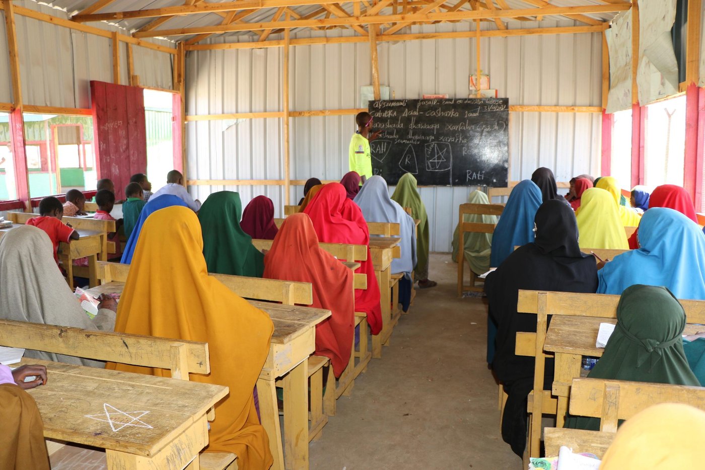 Norwegian Refugee Council constructed a primary school in Barsanguni village in Kismayo town, lower Jubba region. The school comprises of four temporary classrooms, an office, four gender-segregated latrines and child friendly space.
Both local community and Jubbaland state’s Ministry of Education actively engaged in the site identification, mobilization, enrolment of students, and construction of the primary school for the vulnerable host-communities.
A total of 587 students (320 boys, 267 girls) were enrolled and are currently attending morning and afternoon classes. The school uses the recently launched Somali curriculum and operates up to grade-3. The school has 5 teachers who are provided with teacher incentives by NRC.
Nine community education committees (CEC members) 3 of them females have been given capacity building training on school management, leadership and CEC roles. The CEC members are currently taking part in the day to day management of the primary school.
Children in Barsanguni didn’t have opportunity to attend to school due to lack of school in the area. Before the collapse of the Siyad Barre regime in 1990, the village only had a 2 classroom school those were later destroyed by the warring sides during the civil war. The village had no school since then, leaving hundreds of children without education.
Somalia has one of the lowest primary school enrolment rates in the world. More than three million children in Somalia are out of school. Those in South and Central Somalia are affected the worst. Parents are not able to fund their children’s education. In addition to poverty, long distances to school, and safety concerns.
The Integrated protection solutions for women and children affected by displacement is a project that seeks to substantially reduce challenges that are impeding the protection and recovery potentials of women and children affected by displacement
To achieve this overarching goal, specialized protection services are combined with tangible assistance packages to assist displacement affected communities develop resilient capacities necessary to address protection issues affecting women and children.
Specific priorities include ensuring displacement affected children and youth learn in protective and child-friendly environment, strengthening and expanding prevention and response to Sexually Gender Based Violence (SGBV) and access to protection services for IDPs, and consolidating recovery potentials for displaced women and youth. A total of 20,204 individuals are targeted across four hotspot districts in Jubaland (Kismayo) and Somaliland (Buroa, Hargeia, and Erigavo). This project is generously funded by King Salman Humanitarian Aid & Relief Centre (KSrelief).
Photo: Abdulkadir/NRC.