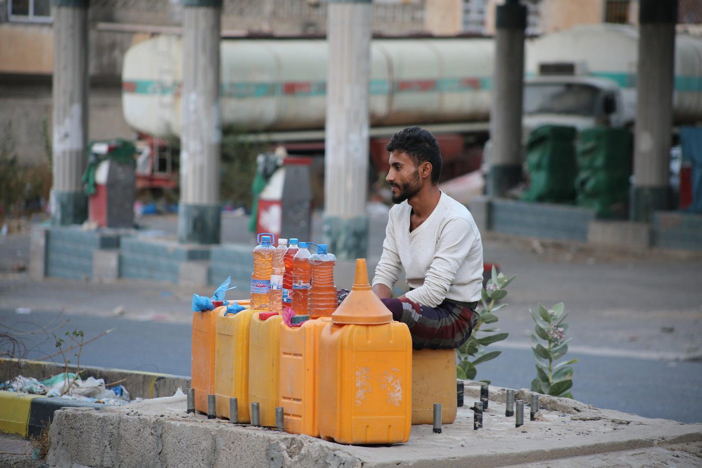 Mohammed Qaid, 20-years old, sells fuel in Taiz city near a closed petrol station. Fuel shortages are common in Yemen and affect cars, hospital generators, and water pumps. Petrol on the black market can be sold for more than two times the official price. "Before the war, I was a student and didn't know anything about fuel. There was no black market. Now I sell fuel on the street. When stations are closed, people depend on the black market to refill their cars and motorcycles".
Photo: Khalid Al-Banna / Norwegian Refugee Council