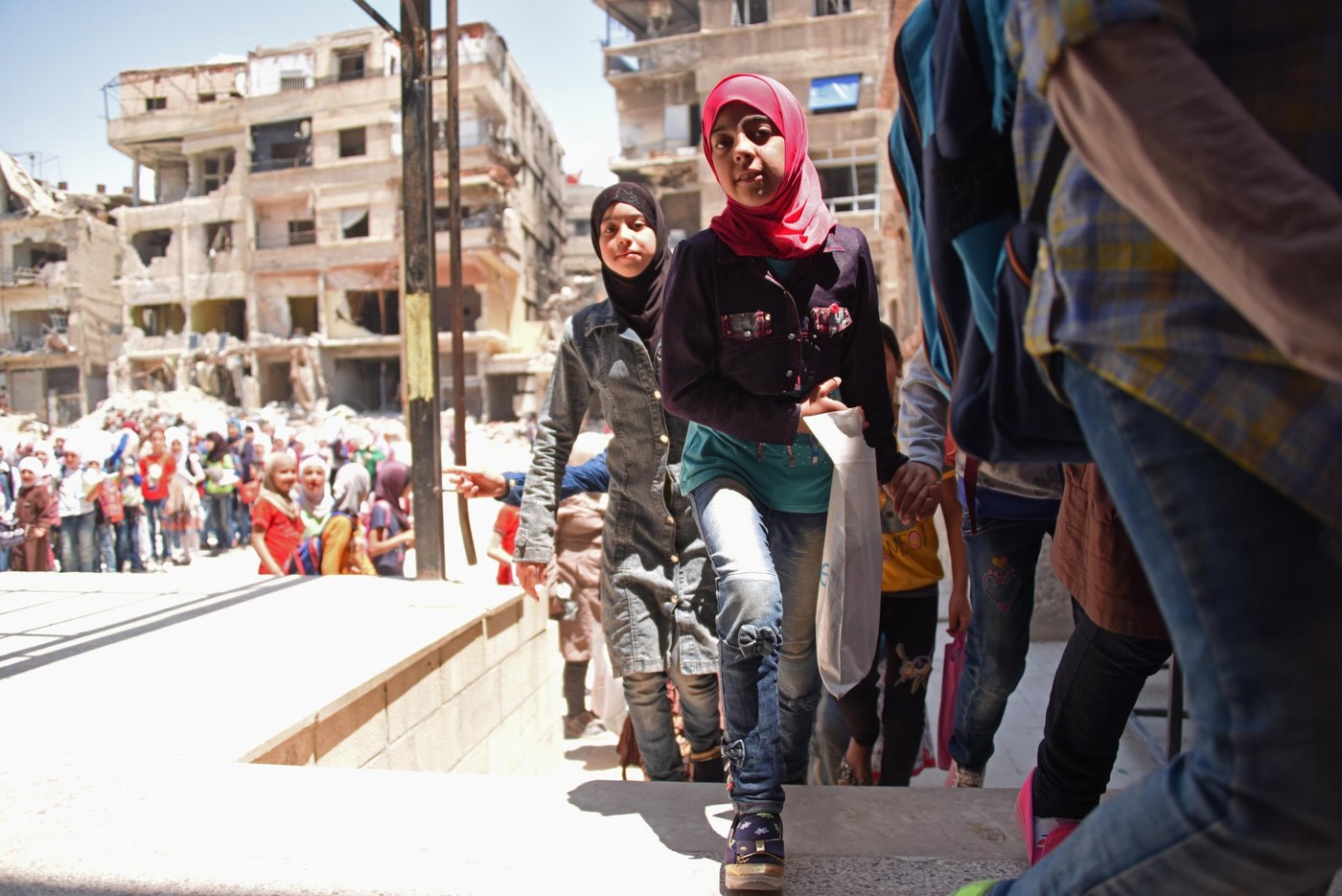 Children living in Harasta, Eastern Ghouta, flock to school to catch up on years of missed education. Years of siege ended with a peak in fighting last March. With most of the neighbourhood in ruins, tens of thousands of Syrians are still displaced with no home to return to, but hundreds have also returned to what remains of their houses or stayed all along.
Despite all they have been through, these children are happy to be back to school. This one in Harasta houses 725 children, with parts of it completely destroyed and others badly damaged.
Photo: Karl Schembri/NRC