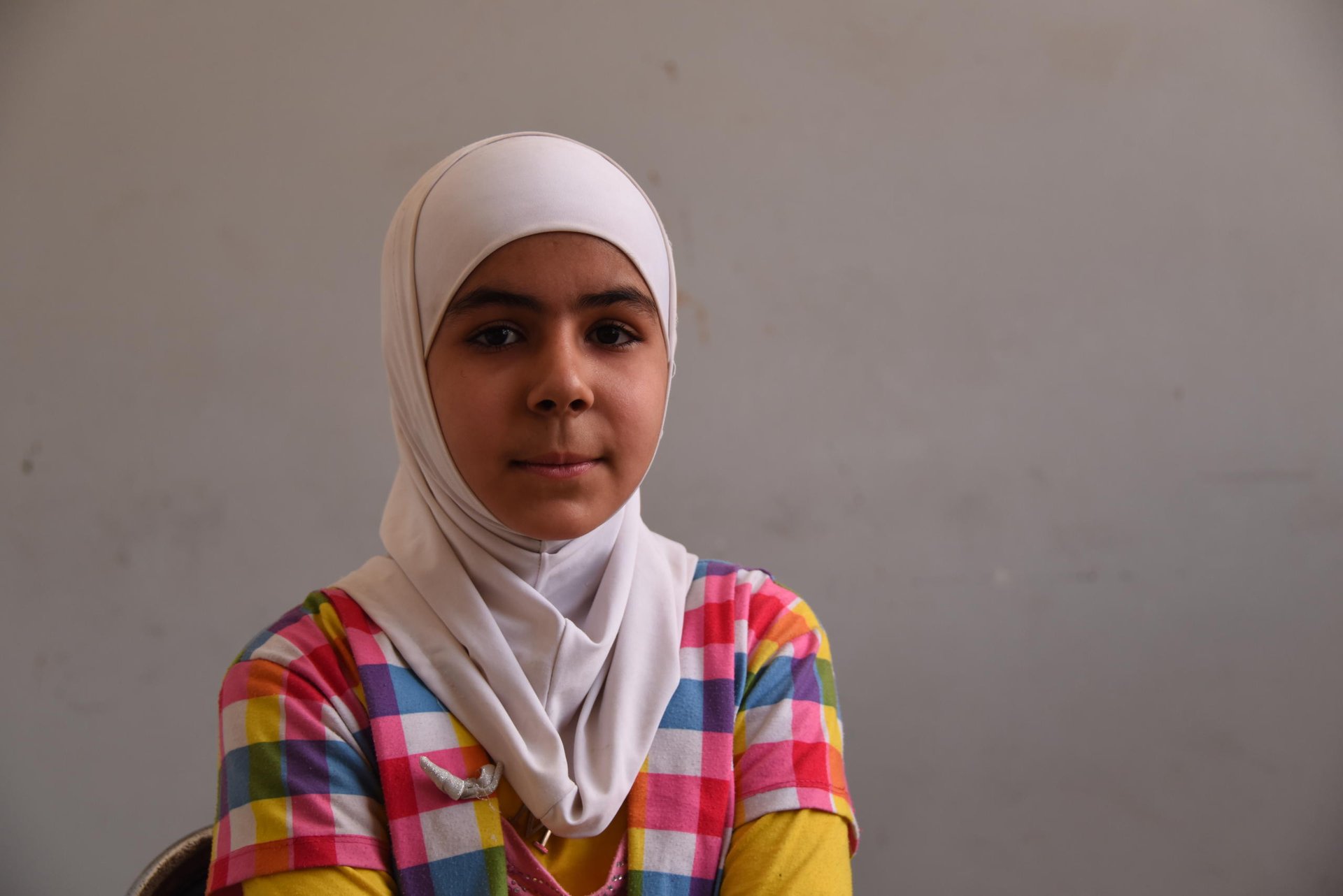 Rawa, 12, from Harasta, Eastern Ghouta
“We were living in hunger and fear. We were under siege. We were staying in the basement. Whenever we heard missiles or airstrikes, we would go to the basement until things calmed down, then we would go upstairs and sleep in our home. We were terrified. My young siblings used to scream and cry.
“We were under an intensive siege, what we felt was unspeakable. When this crisis started we were half way through the school year and we stopped.
“I like to write and study when I am in the basement. I also revise the subjects I took.
“My younger brother Omar, just like most of the children, used to study normally. But when we started sitting in the basement, along with fear, hunger and the siege, he forgot some letters. We are helping him learn them again. He doesn’t understand everything we teach him properly. 
“What is most important is peace and safety. We would like you to repair our school and provide us with water and electricity.”
Photo: Karl Schembri/NRC