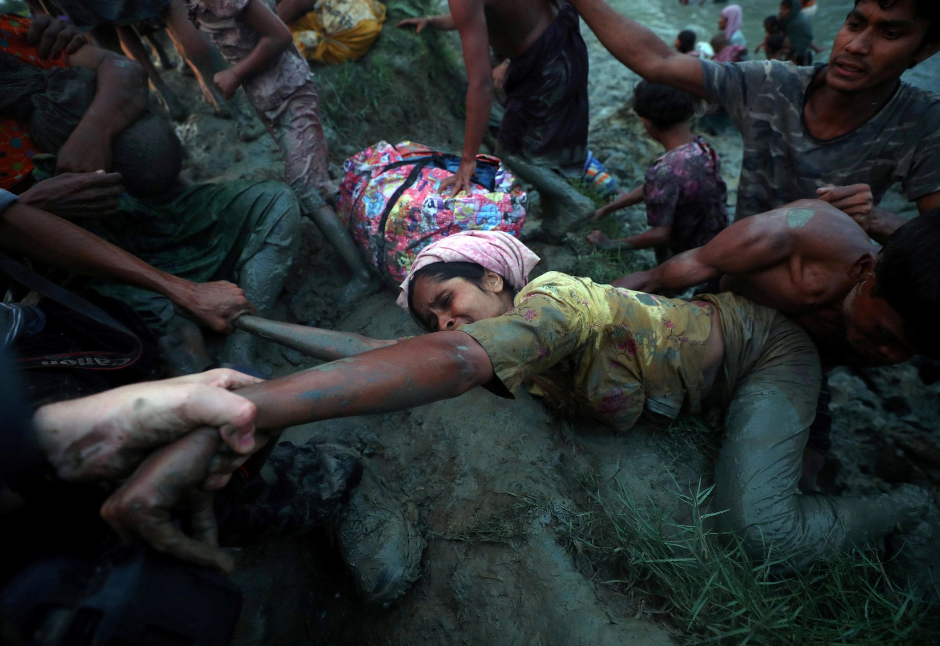 Photographers help a Rohingya refugee to come out of Nad River as they cross the Myanmar-Bangladesh border in Palong Khali, near Cox's Bazar, Bangladesh, November 1, 2017. Hannah McKay: "We were standing, looking out over paddy fields and grasslands - lots of water and one thin path leading to the border with Myanmar. In the distance we could see a huge group of people. But they weren't moving. It was 4 o'clock in the afternoon with only two hours of daylight left. So we decided to move towards them. It took us about an hour along the muddy path, meeting border guards and persuading them to let us pass. Then we saw thousands of refugees just sitting there, with more Bangladeshi border guards telling us to go back. We could see something was going on behind the crowd. So we waited for an opportunity to move closer, and that's when we saw them. The crowd was sitting on a riverbank and behind them, about three metres below, in the river itself, there were just hundreds of refugees coming across every minute. It was non-stop. There was no end to the people. People carrying babies. Elderly people being escorted through the water and mud, more than knee-deep. And we were just photographing everyone coming towards us. Then this woman appeared. She got to the point where she needed to get up to the footpath where we were. But she was exhausted. Two refugee men on her level were trying to push her up, which was when we reached out to help. Reuters photographer, Adnan Abidi, took a hand. Another photographer took another and I got her leg when she got within range. It was a case of dragging her. She lay there for a few minutes. I have no idea what happened to her.  You are there trying to do your job with a camera in your hand. And then your heart overrules your head." REUTERS/Hannah McKay/File photo SEARCH "POY STORY" FOR THIS STORY. SEARCH "REUTERS POY" FOR ALL BEST OF 2017 PACKAGES. TPX IMAGES OF THE DAY.