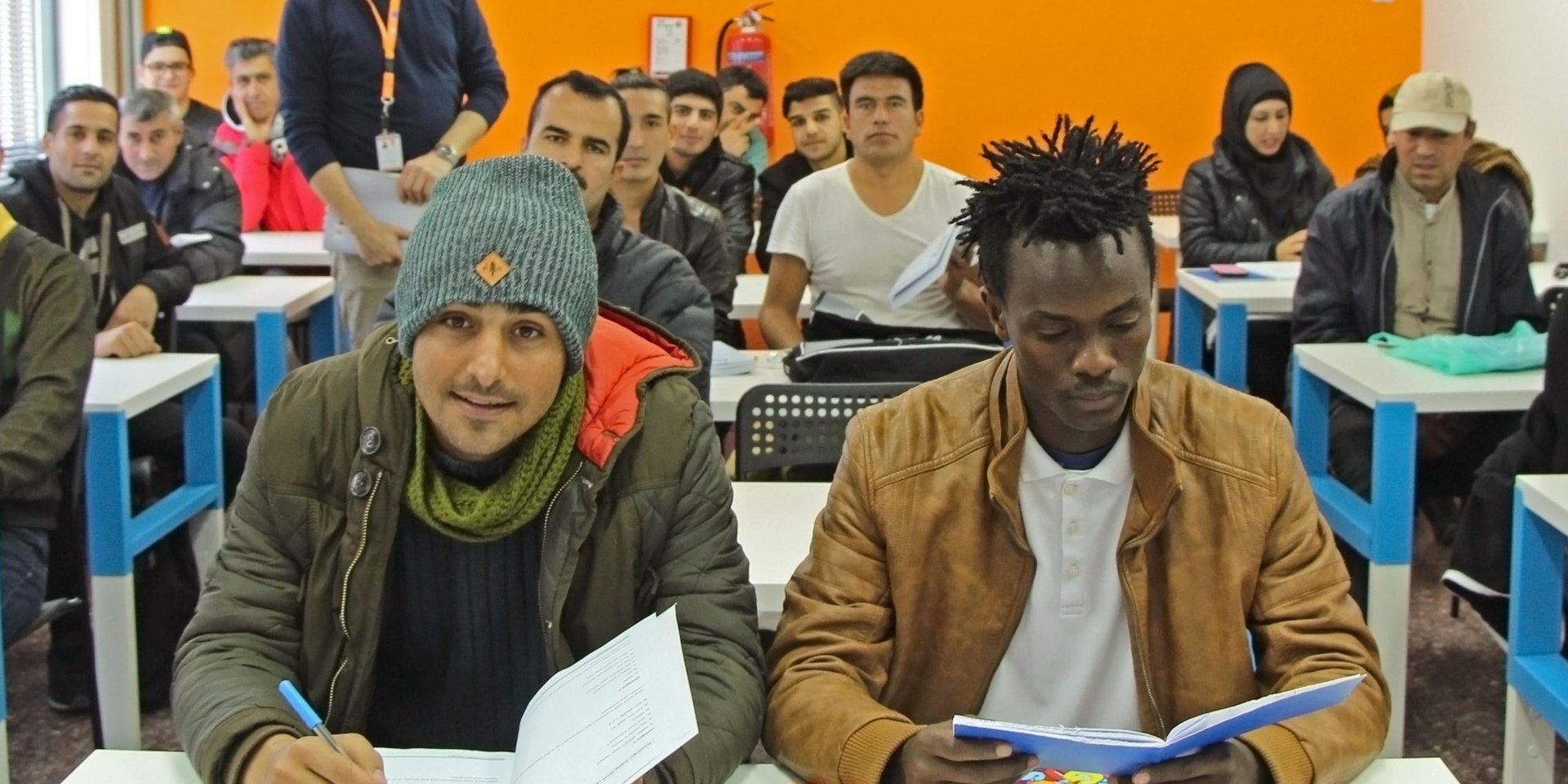 Sekou Kumara (right), 18, sits at the front of his English class in Thessaloniki as teacher Vassilis Papadopoulos looks on. Photo: Maria Gounaridou/NRC