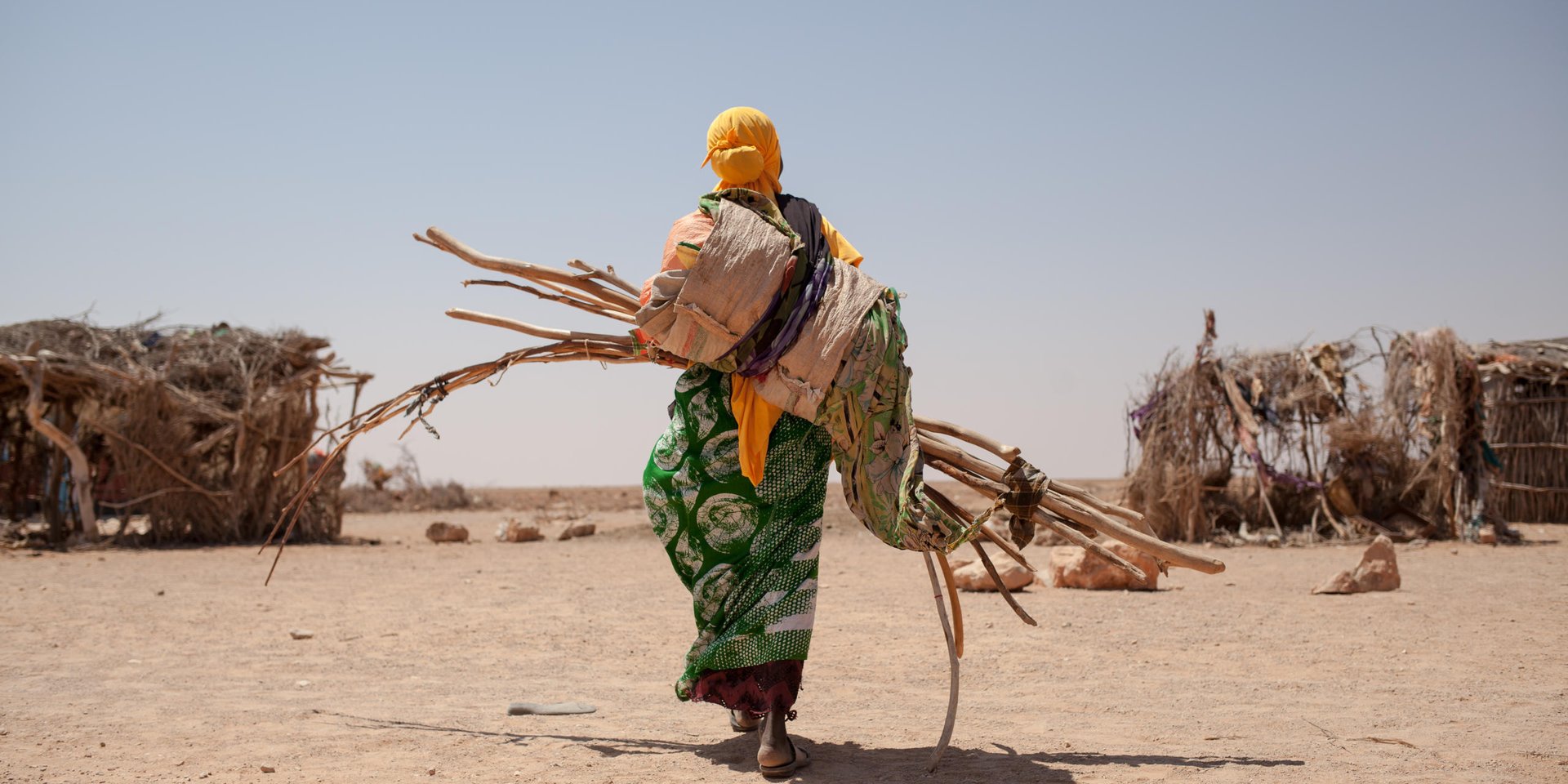 Somalia. Photo by Adrienne Suprenant.  On the side of the road going from Burao to Erigavo in the Sanaag region, the little village of Shisha counts 60 newly arrived internally displaced families. It almost doubled the village population on a very short period of time. 

Miglo Barre, carrying the wood, fabric and cords necessary to build her tent just arrived. She walked four hours, crossing the mountains bordering the dry valley. From her 200 sheeps, nothing is left. Sick from the lack of food, her husband is now in Garadag's hospital, leaving her alone to care for their five children. 

She will look for a place to build the tent, and when done, will go back on the other side of the mountain, and come back walking with her children. She is hoping to receive help from the muslim community or from NGO's as she stays closer to the road, and not in an isolated valley as she used to.