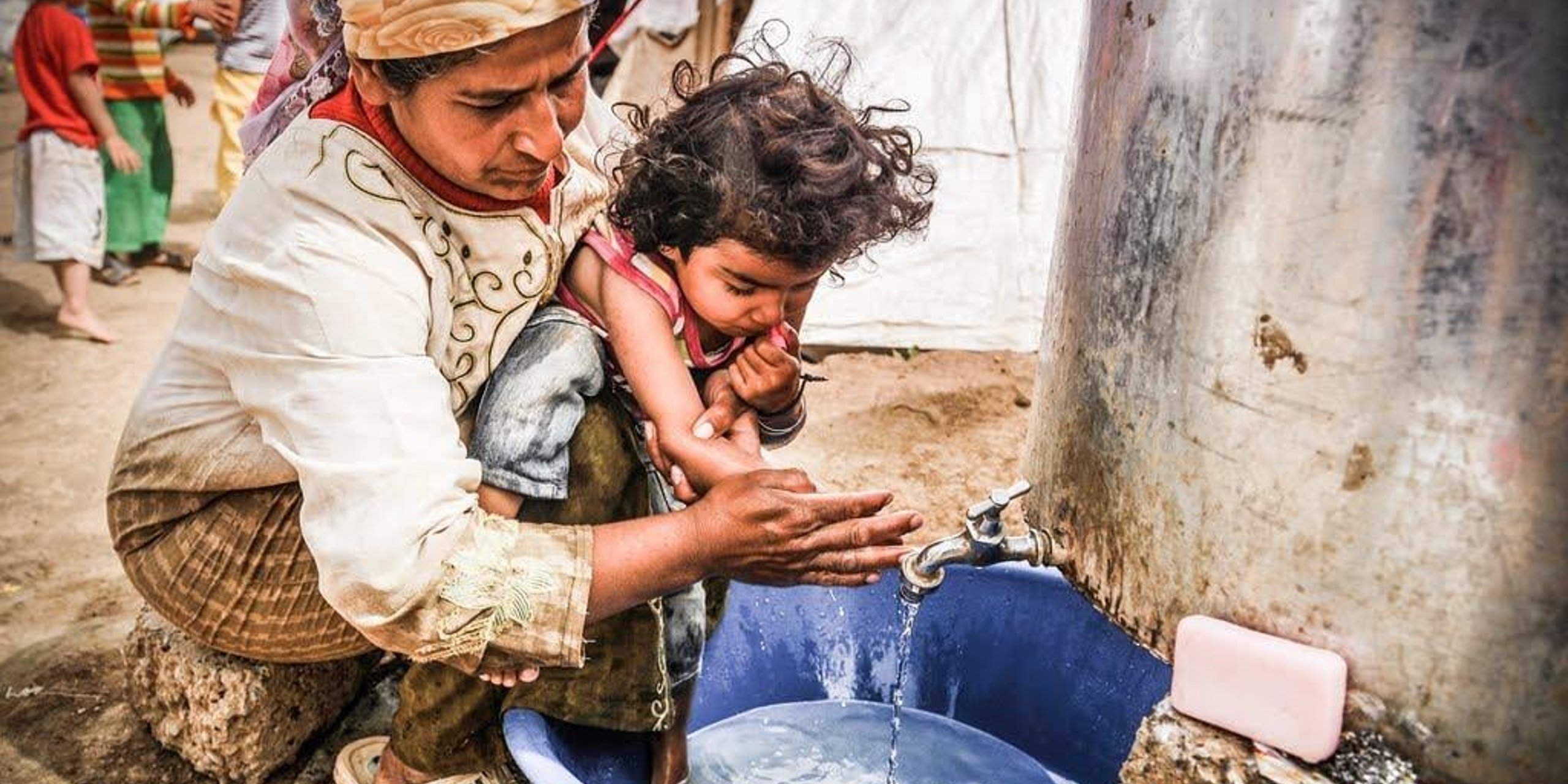 Hazina, 37, helping her youngest child, 4-year-old Lolo, wash her hands. Lolo is developmentally disabled and cannot walk, but Hazina has not received any assistance to address Lolo’s special needs. Photo: NRC/Christian Jepsen
