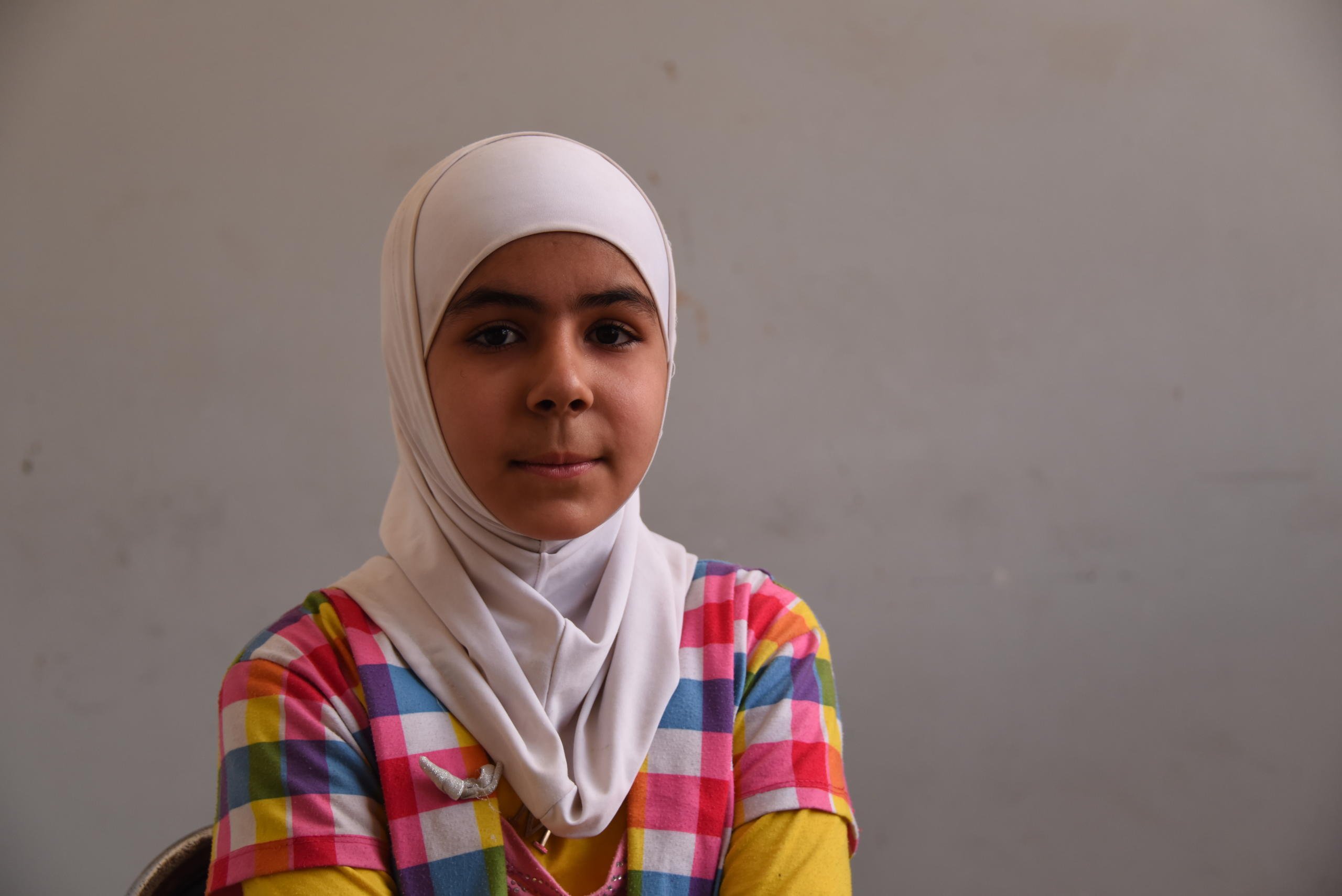 Rawa, 12, from Harasta, Eastern Ghouta
“We were living in hunger and fear. We were under siege. We were staying in the basement. Whenever we heard missiles or airstrikes, we would go to the basement until things calmed down, then we would go upstairs and sleep in our home. We were terrified. My young siblings used to scream and cry.
“We were under an intensive siege, what we felt was unspeakable. When this crisis started we were half way through the school year and we stopped.
“I like to write and study when I am in the basement. I also revise the subjects I took.
“My younger brother Omar, just like most of the children, used to study normally. But when we started sitting in the basement, along with fear, hunger and the siege, he forgot some letters. We are helping him learn them again. He doesn’t understand everything we teach him properly. 
“What is most important is peace and safety. We would like you to repair our school and provide us with water and electricity.”
Photo: Karl Schembri/NRC