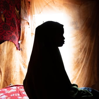 Flicka sitter i mörkret. 