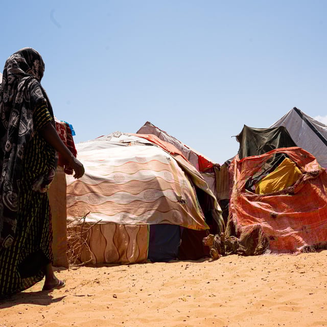 En kvinna går mot sitt tillfälliga skydd i Kahda-lägret i Mogadishu efter att ha flytt torkan i Lower Shabelle, där hennes hem och försörjning har gått förlorade.