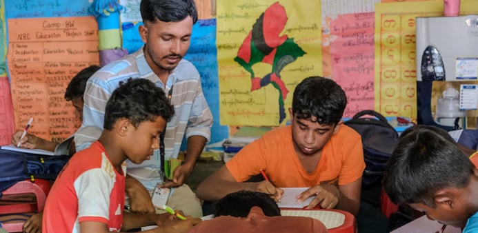 En lärare har uppsikt över sina två elever i klassrummet.