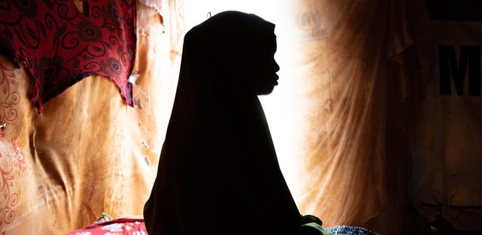 Flicka sitter i mörkret. 