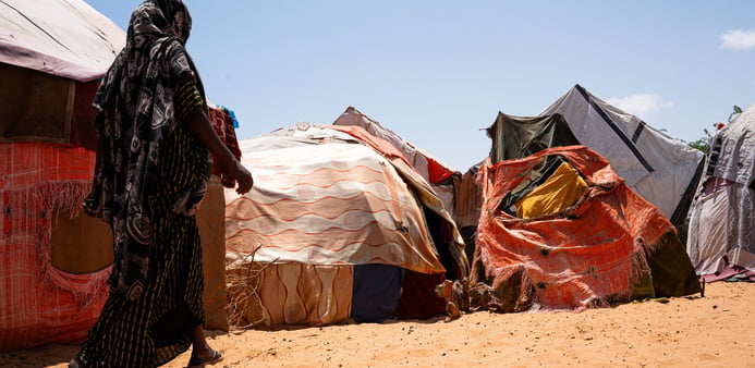 En kvinna går mot sitt tillfälliga skydd i Kahda-lägret i Mogadishu efter att ha flytt torkan i Lower Shabelle, där hennes hem och försörjning har gått förlorade.