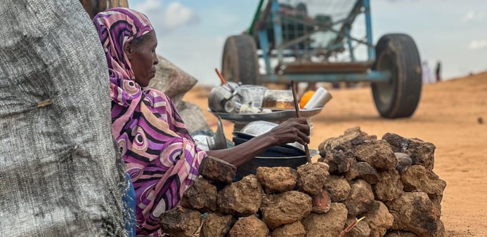 En kvinna sitter ner och lutar sig mot ett träd.
