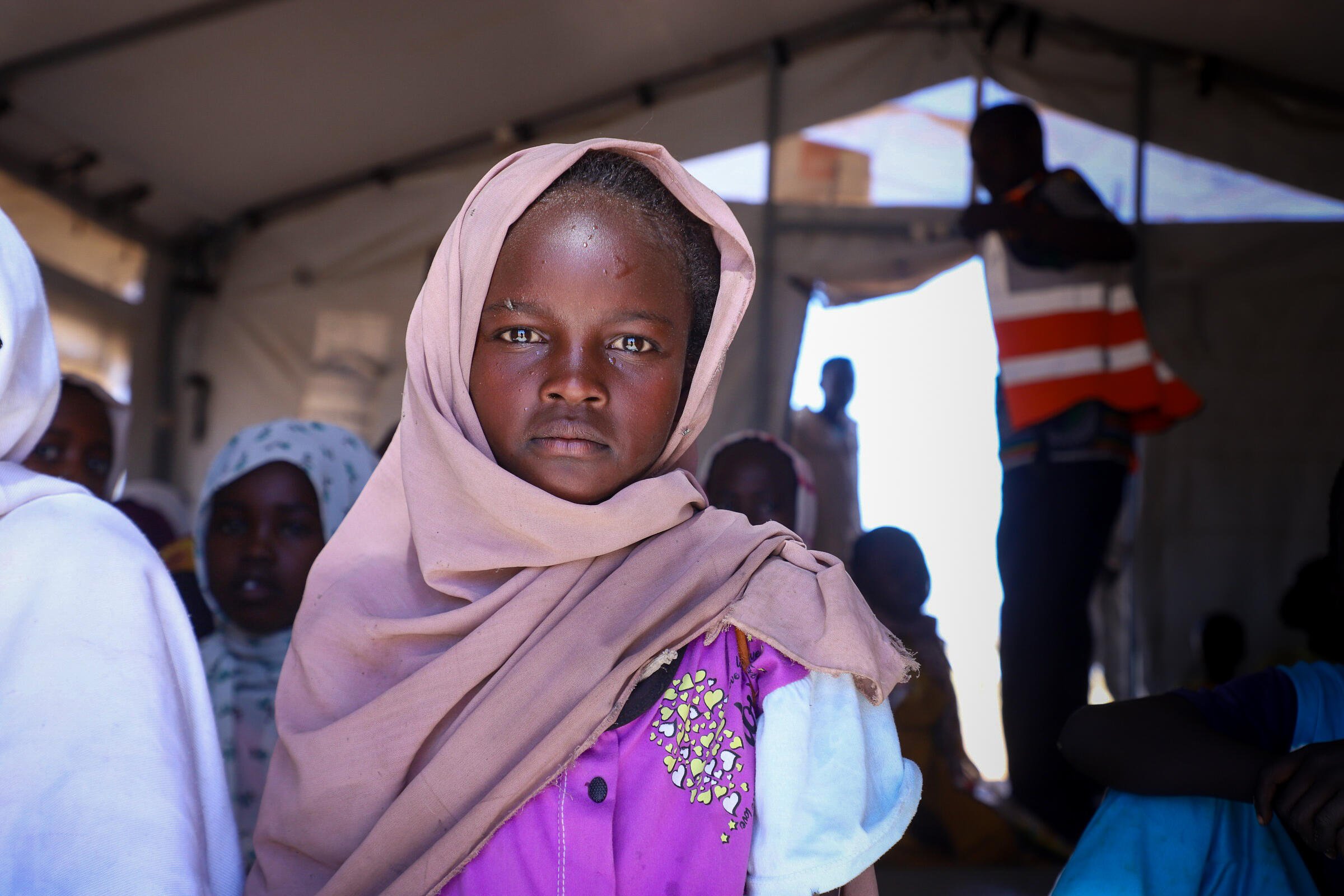 En flicka st&aring;r i ett tillf&auml;lligt t&auml;lt i ett omr&aring;de dit m&auml;nniskor har flytt efter konflikt och os&auml;kerhet.