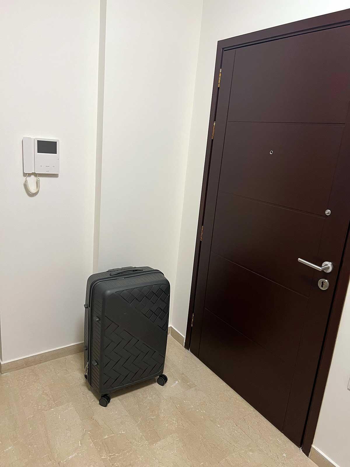 En resv&auml;ska st&aring;r p&aring; golvet i en l&auml;genhetshall, intill ytterd&ouml;rren