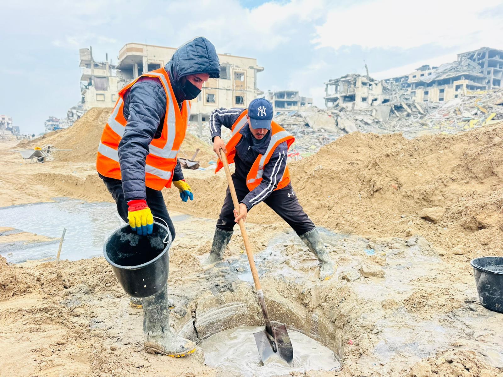 Tv&aring; m&auml;n arbetar utomhus med att rensa bort lera fr&aring;n marken.