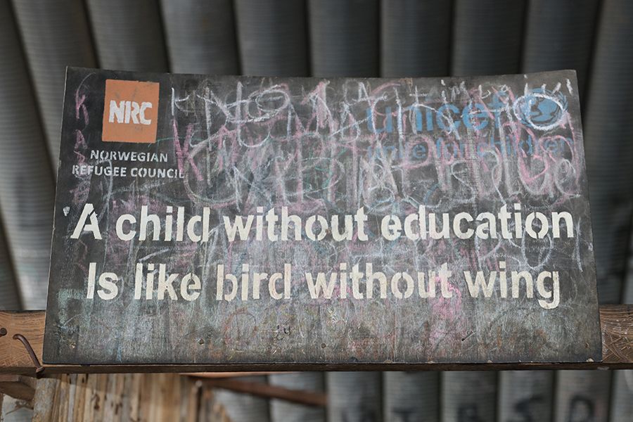 A black sign reading 'A child without education is like a bird without wings'