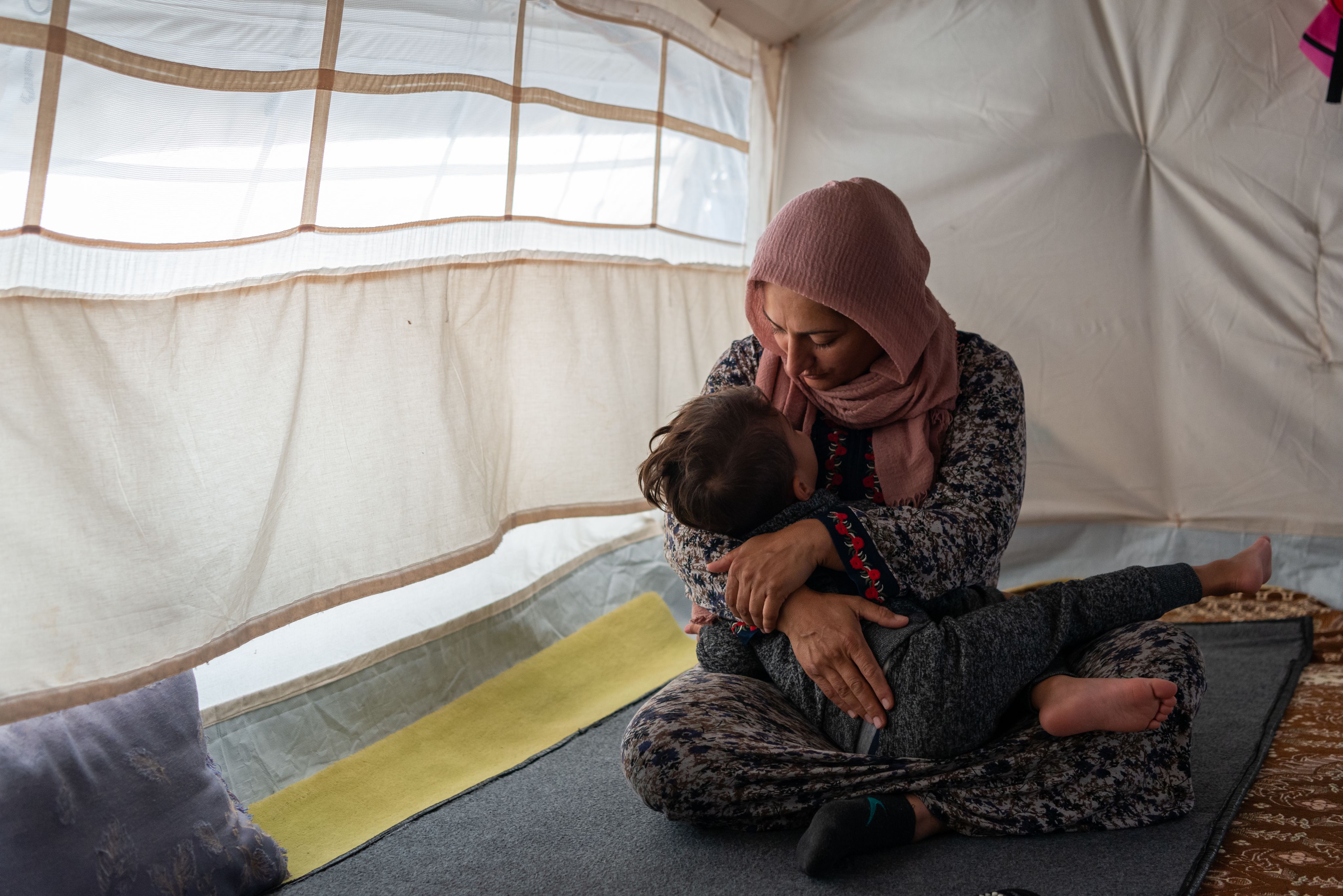 Woman and child cuddle on floor. 