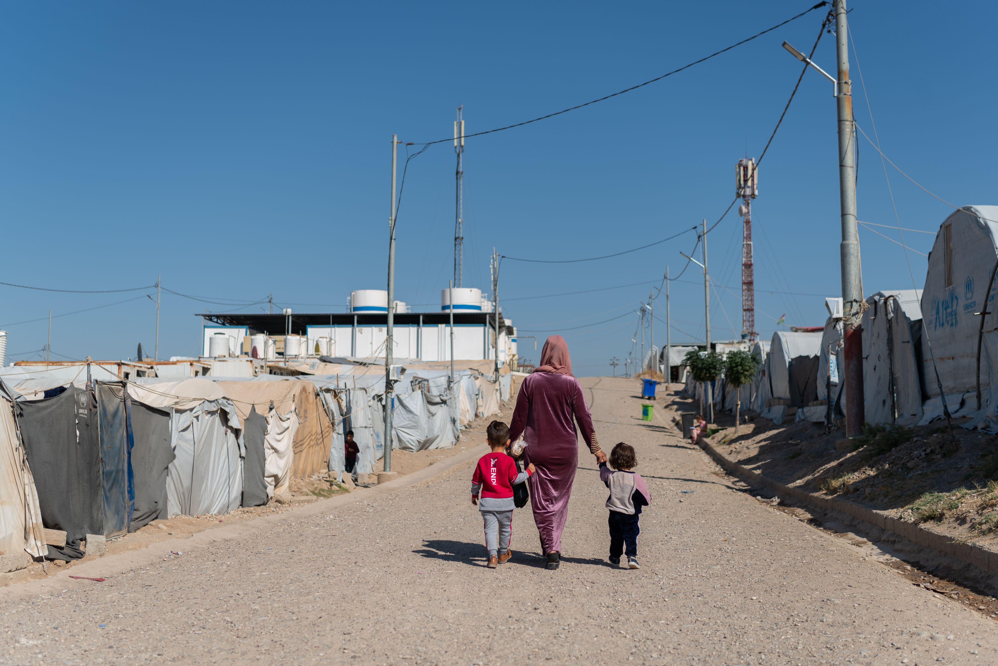 Woman and children walking in refugee camp. 