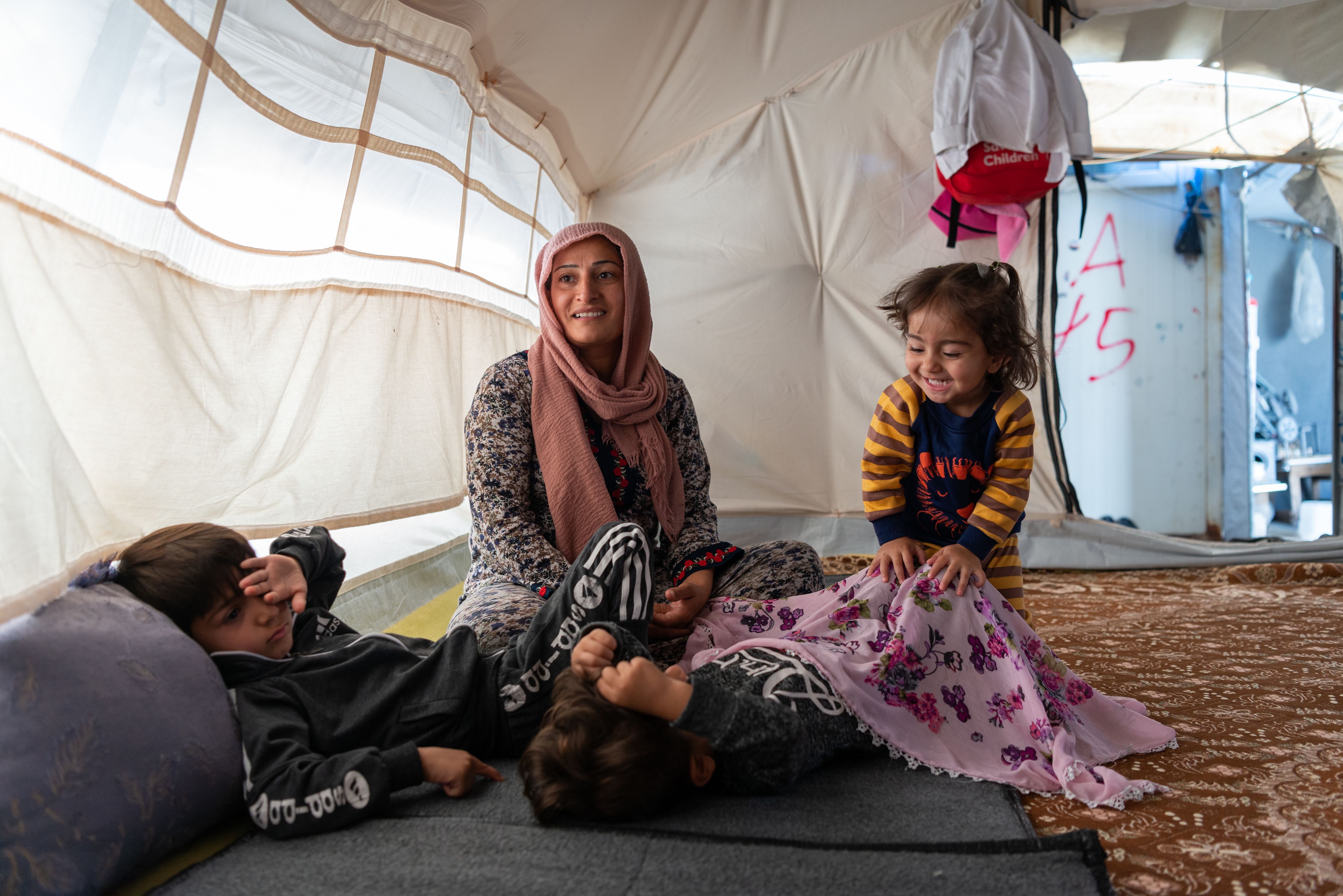 Woman and her children inside a tent.