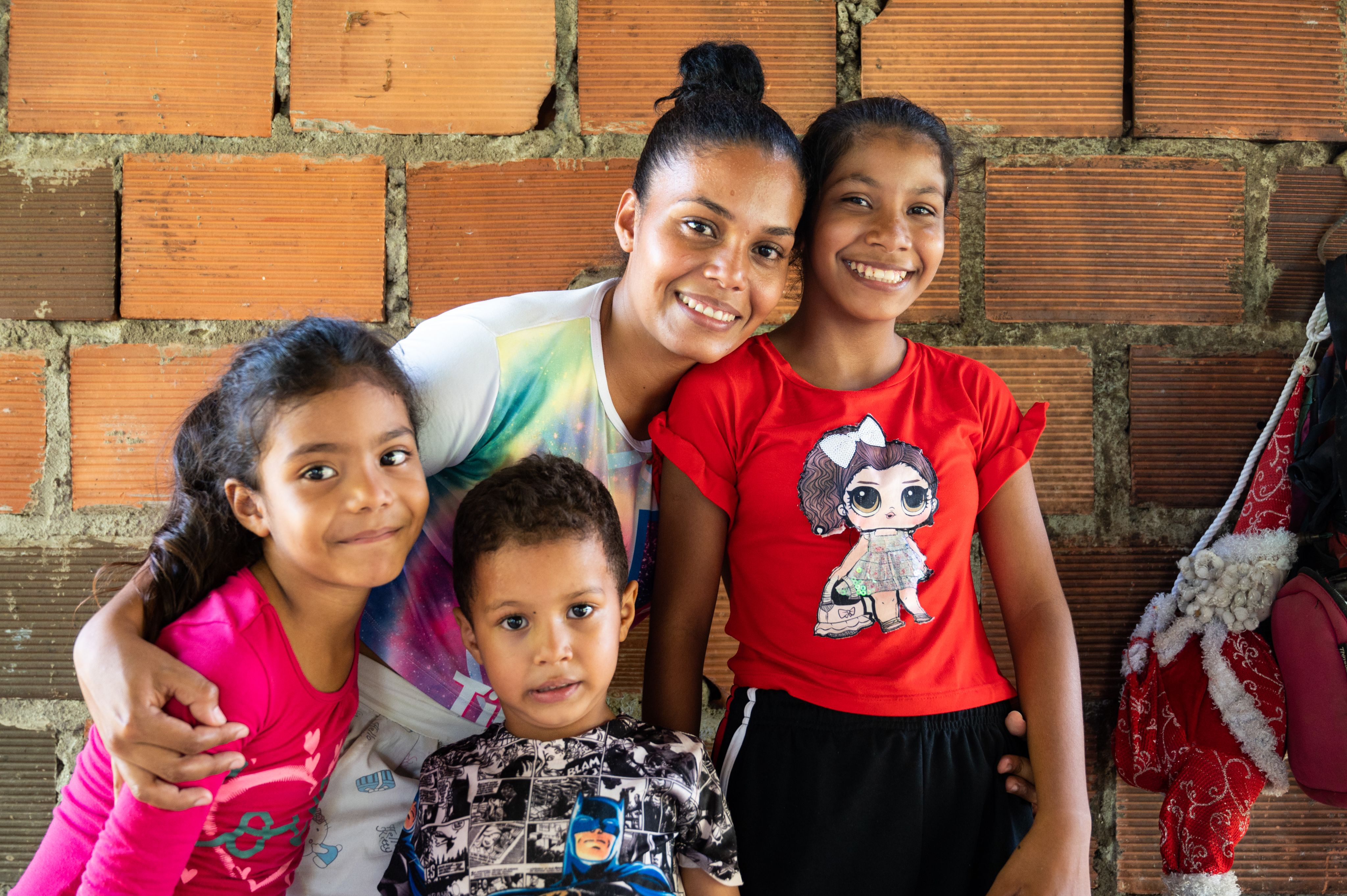 A 27 year old woman, with her three children smiling to the camera.