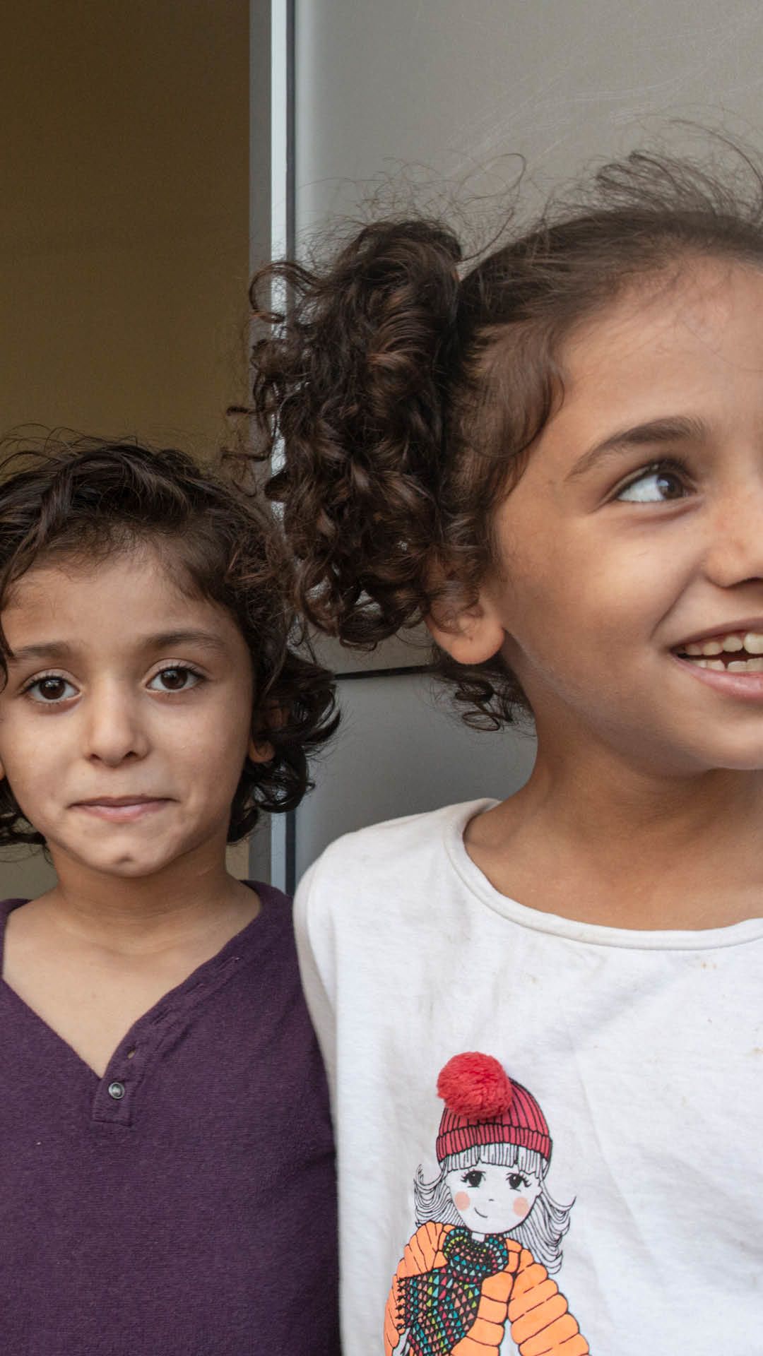 Syskonen Jude, 6 år och Fatima, 7 år fotade i dörröppningen till lägenheten