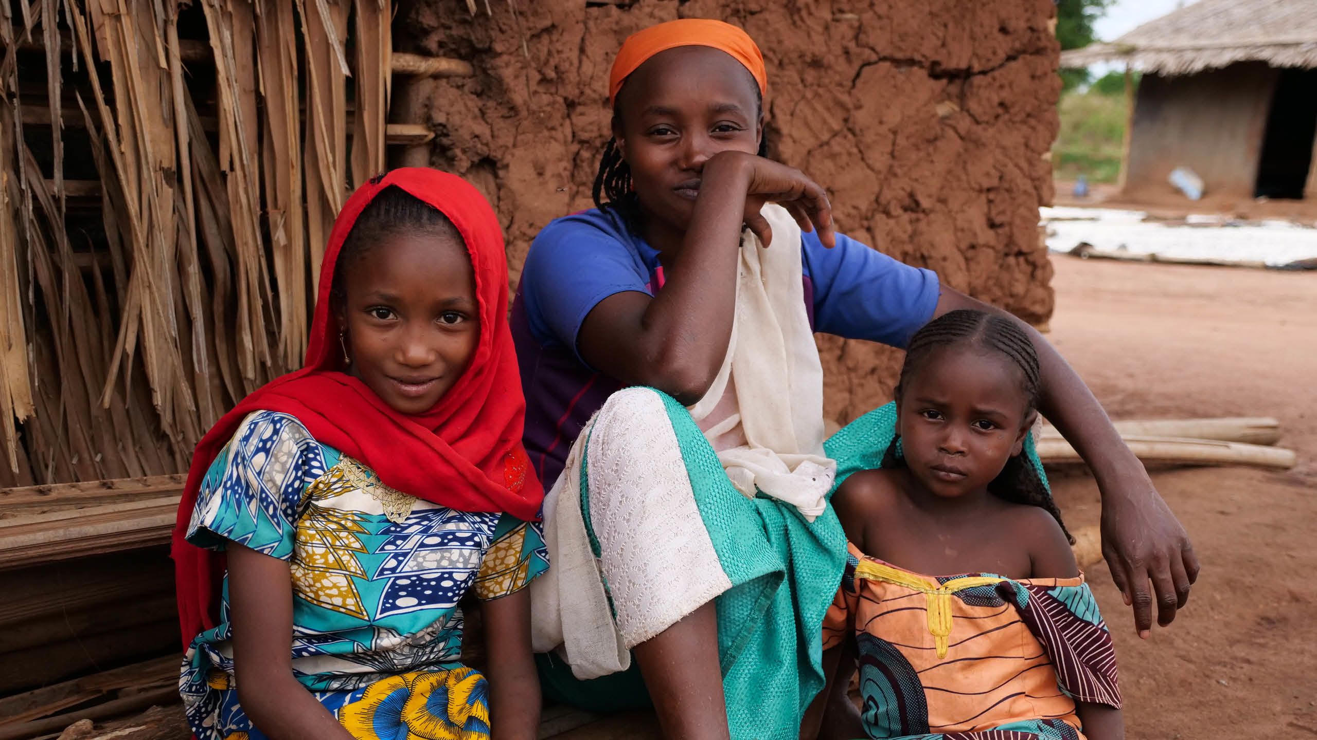 Tre flickor sitter utanför deras hem i byn Gaïna i Kamerun.
