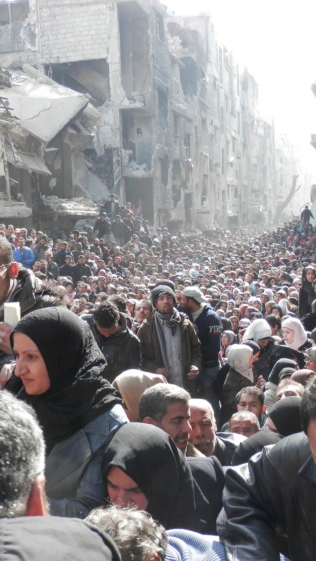 A sea of people pushing through the ruins of the destroyed neighbourhood.