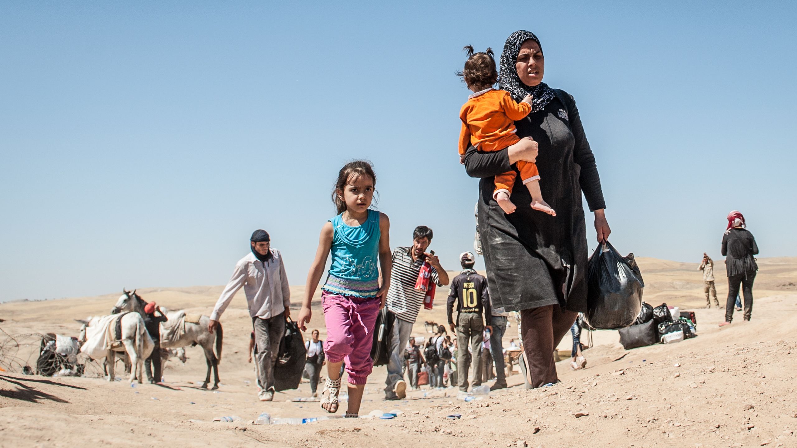 A woman and two children crossing the border from Syria to Iraq on foot.