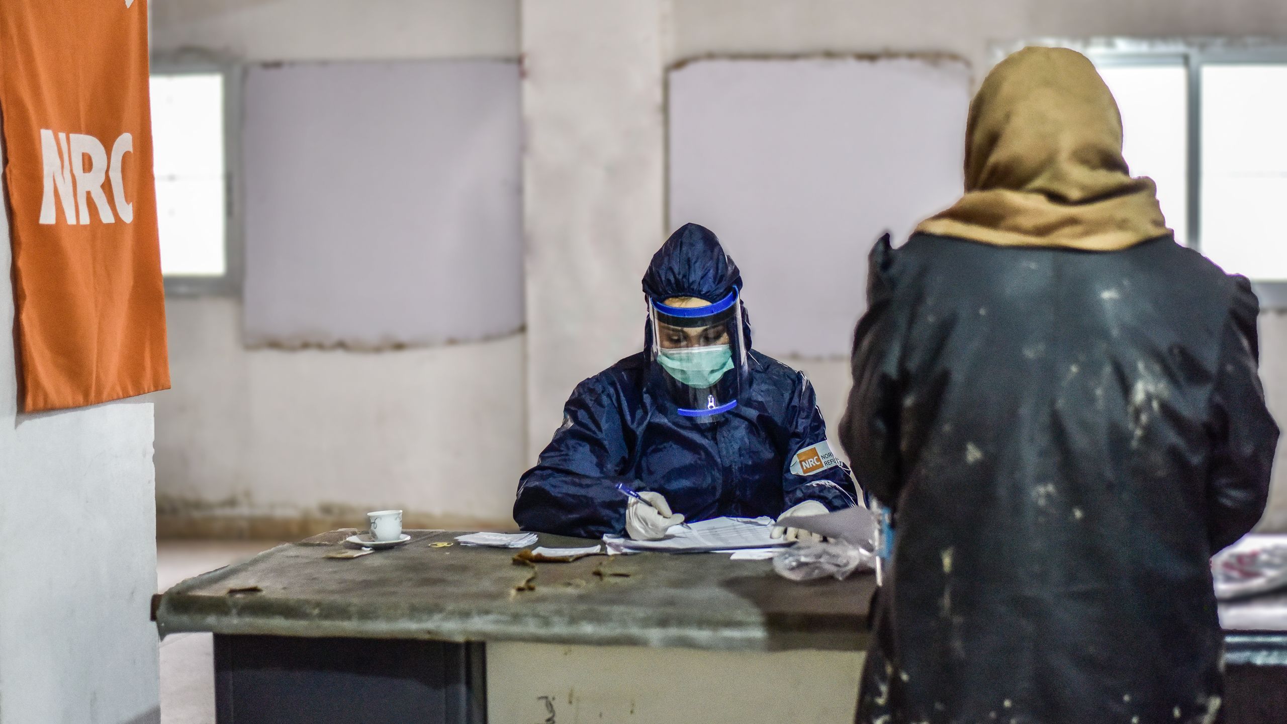 NRC staff in full personal protective equipment is distributing essential relief items to families in need.